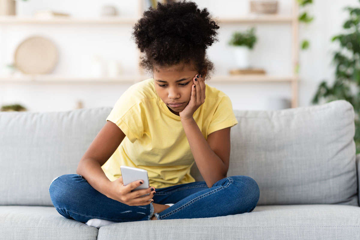 Black teen girl uses smartphone while bored