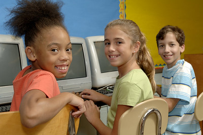 three students posing in front of computers