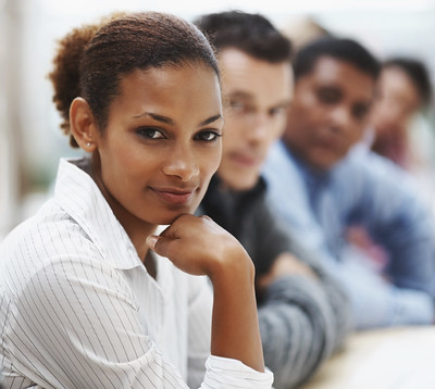 A woman in front of a group of people looks into the camera 