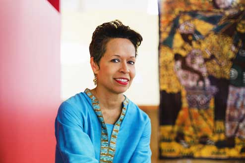 Deborah Holmes smiles at camera. In the background is a yellow and black painting.