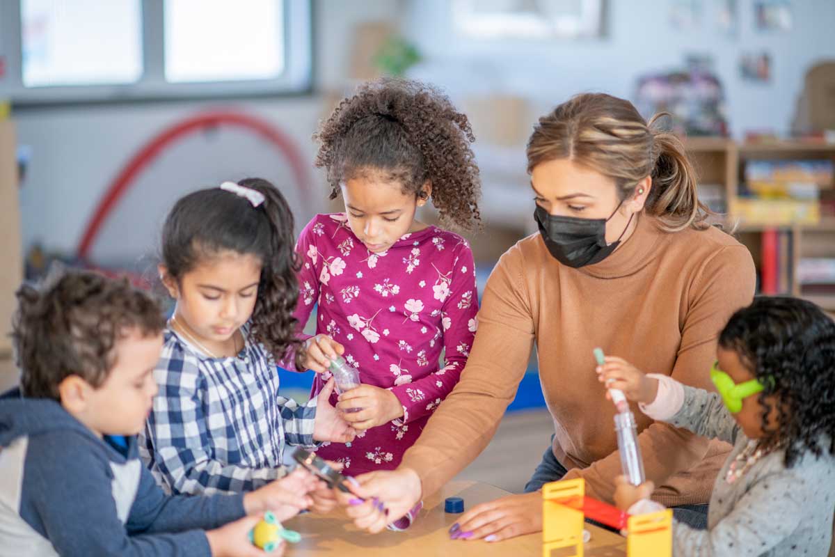 Child care provider tends to children while wearing a mask