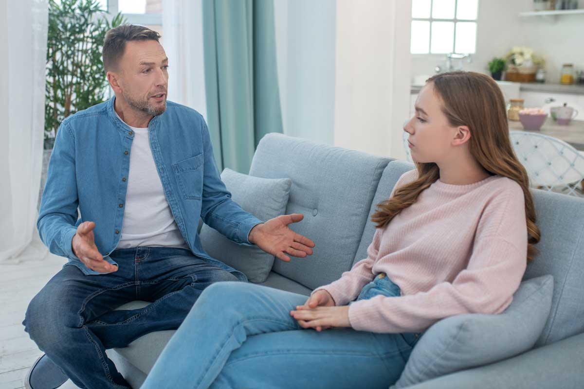 Father talking to daughter on couch