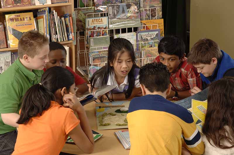 A diverse group of children sitting together at a library table