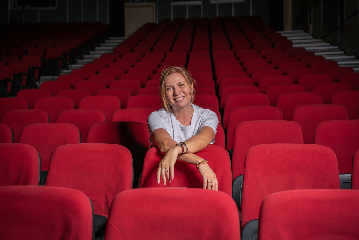 Female director sits in theater.