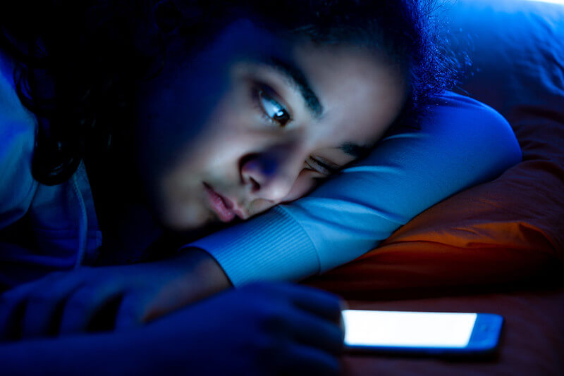 A girl looks sad and tired while using her phone