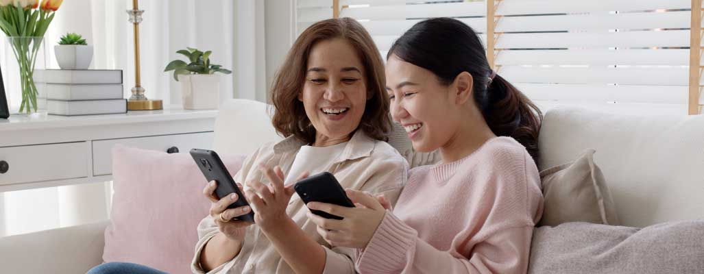 Asian American mother and daughter using smartphones