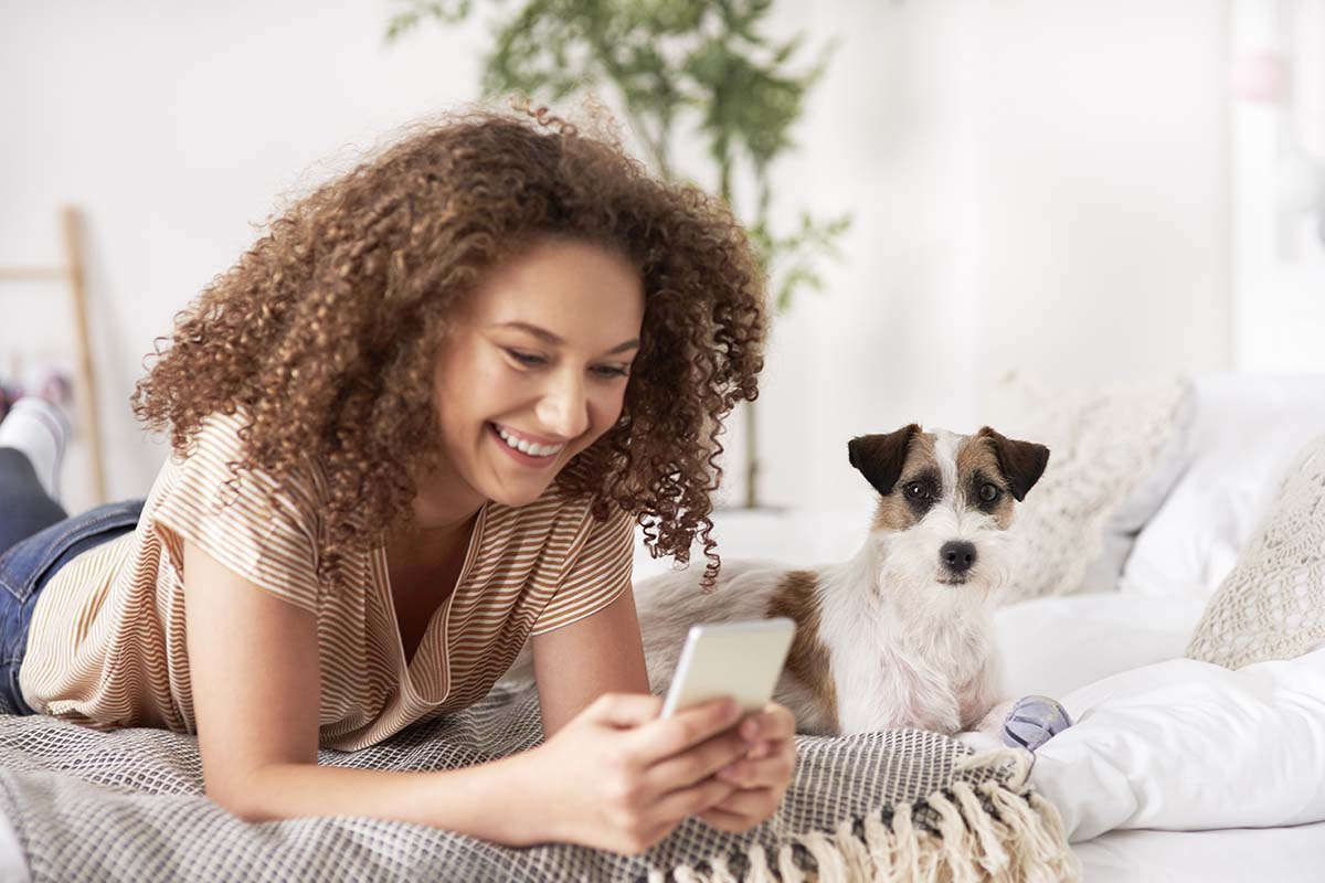 teen girl uses phone with dog