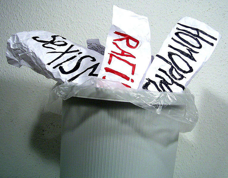 Racism, sexism, and homophobia written on pieces of paper and thrown in the trash